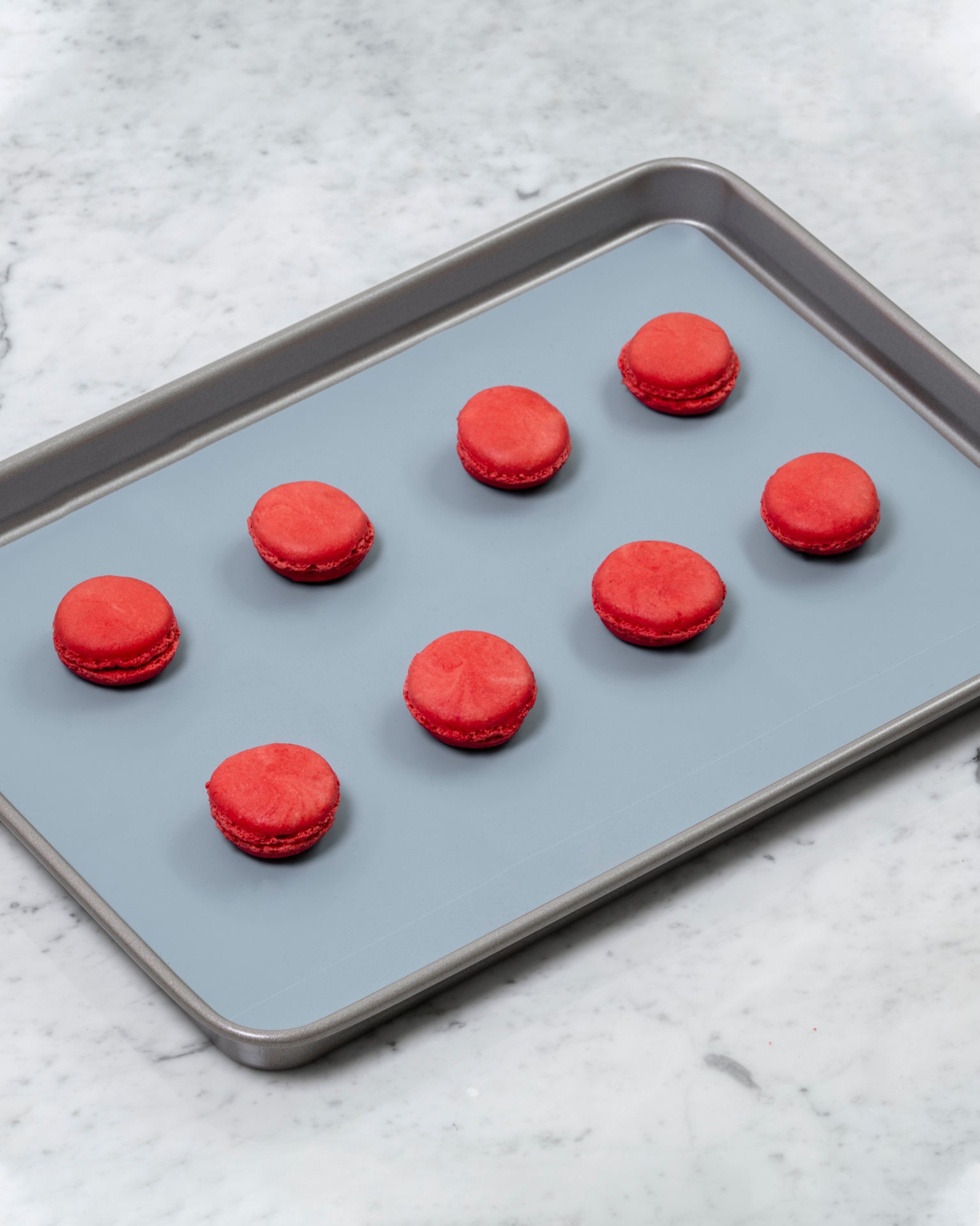 The Slate 12 x 17 Baking mat on a baking tray with red macaroons on it. 