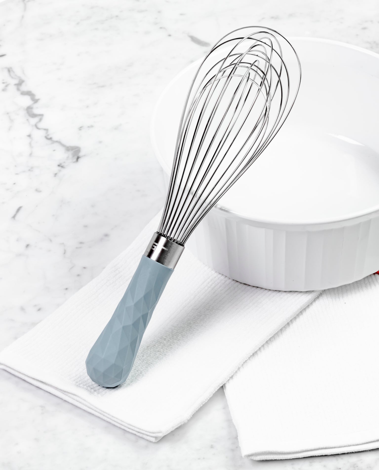 The Slate  Mini Whisk resting on a white kitchen towel next to a white bowl.