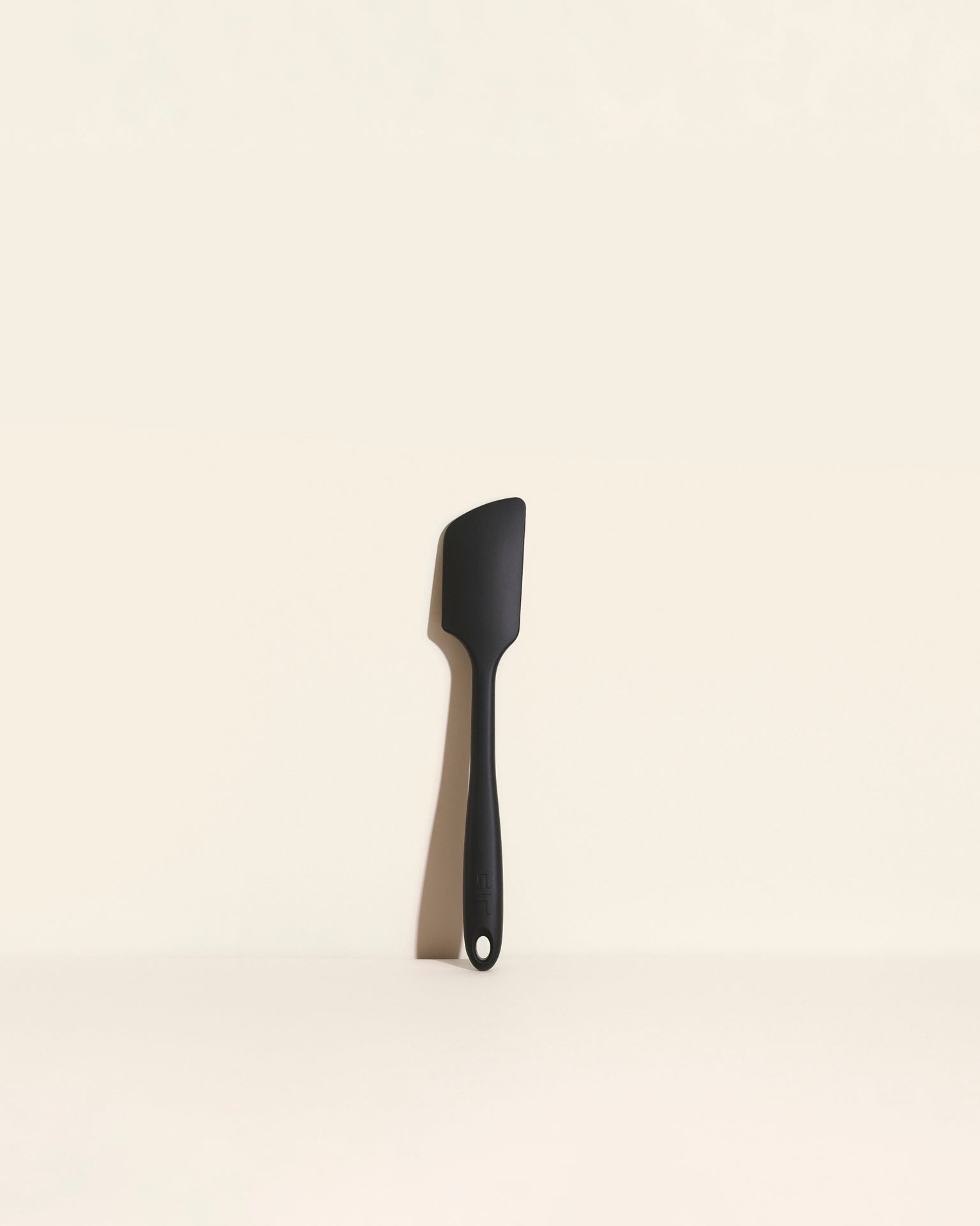 The Black Ultimate Spatula on a cream background. 