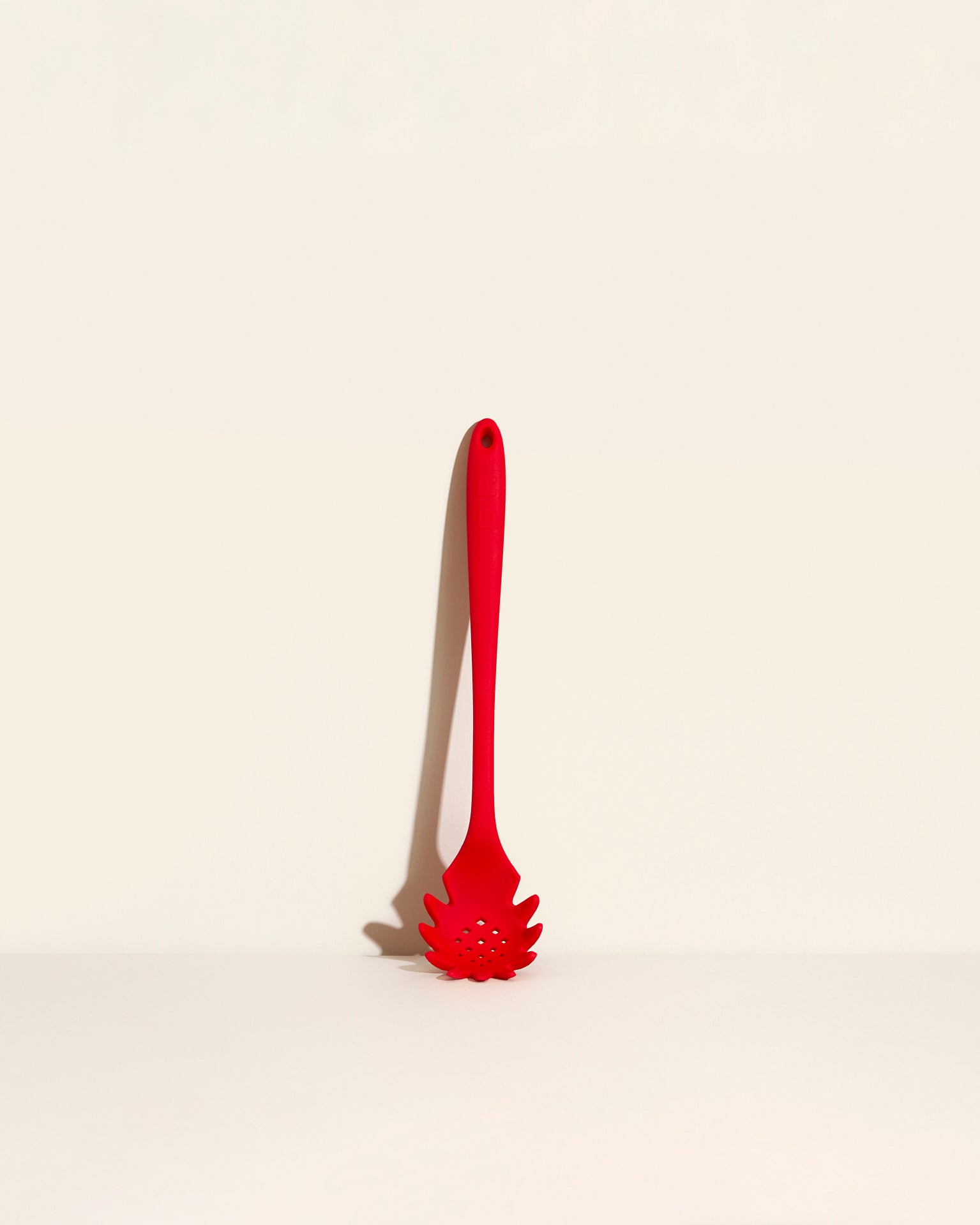 The Ultimate Spaghetti Spoon in Red on a cream background. 