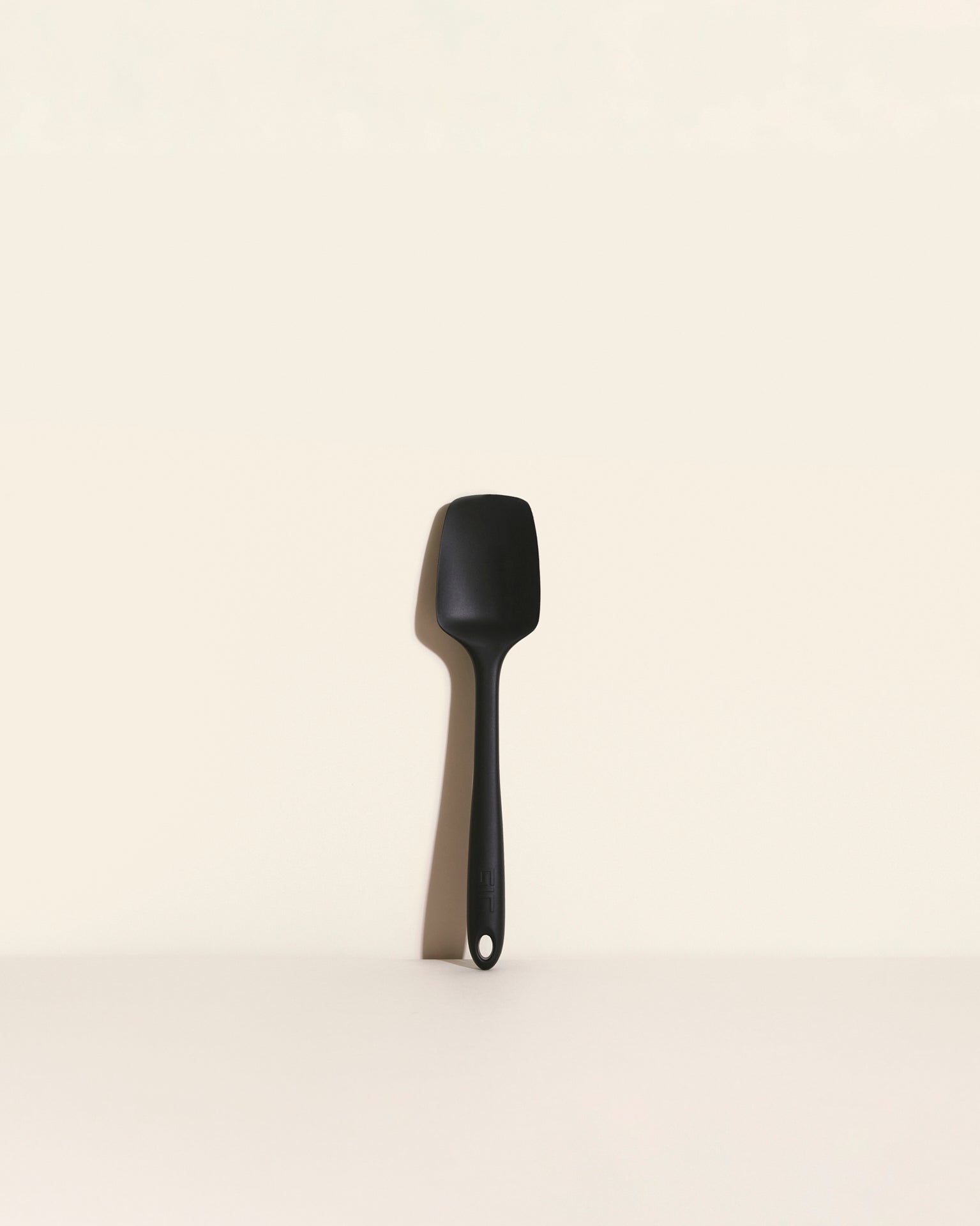The Black Ultimate Spoonula on a cream background. 