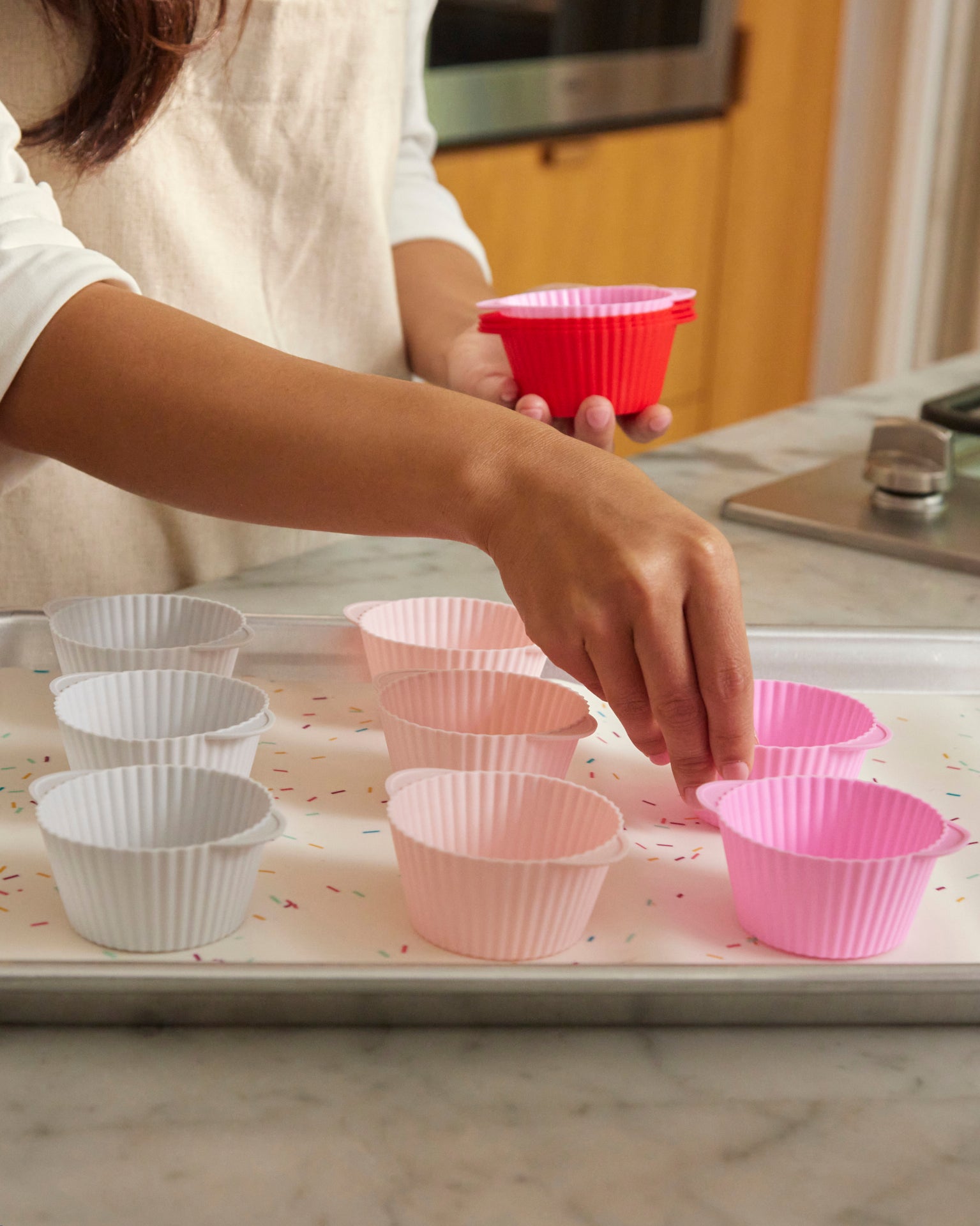 A lady placing the Strawberry Swirl Cupcake Liners on a baking tray. 