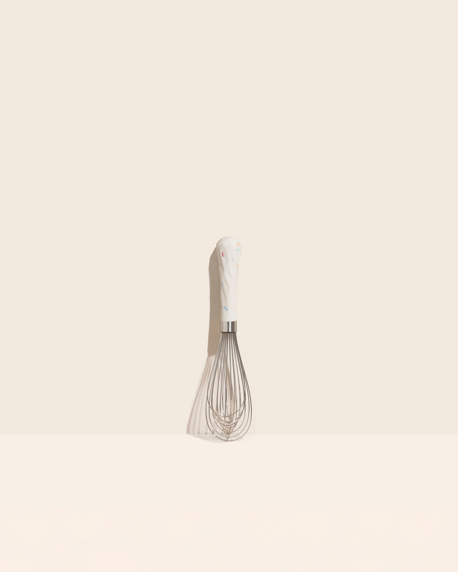 The Sprinkles Mini Whisk on a cream background. 
